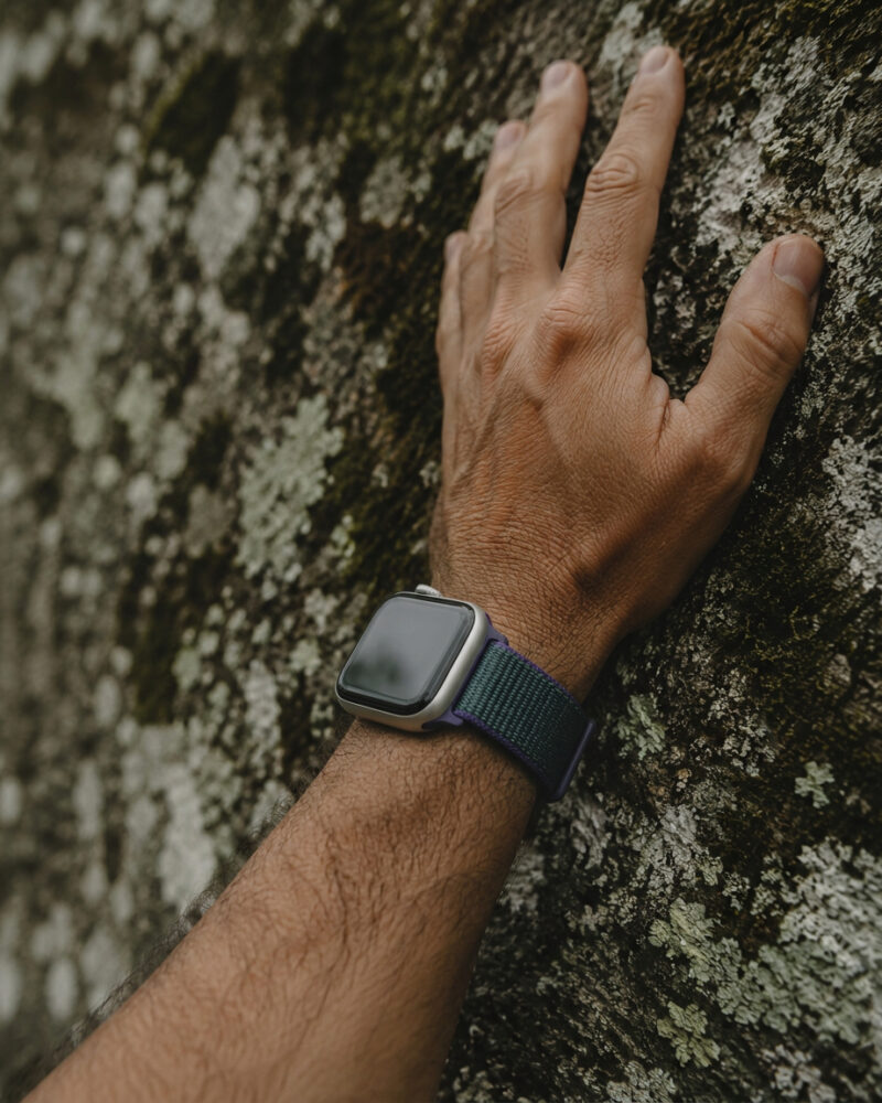 Man wearing smartwatch with midnight fog sport loop band on textured wall