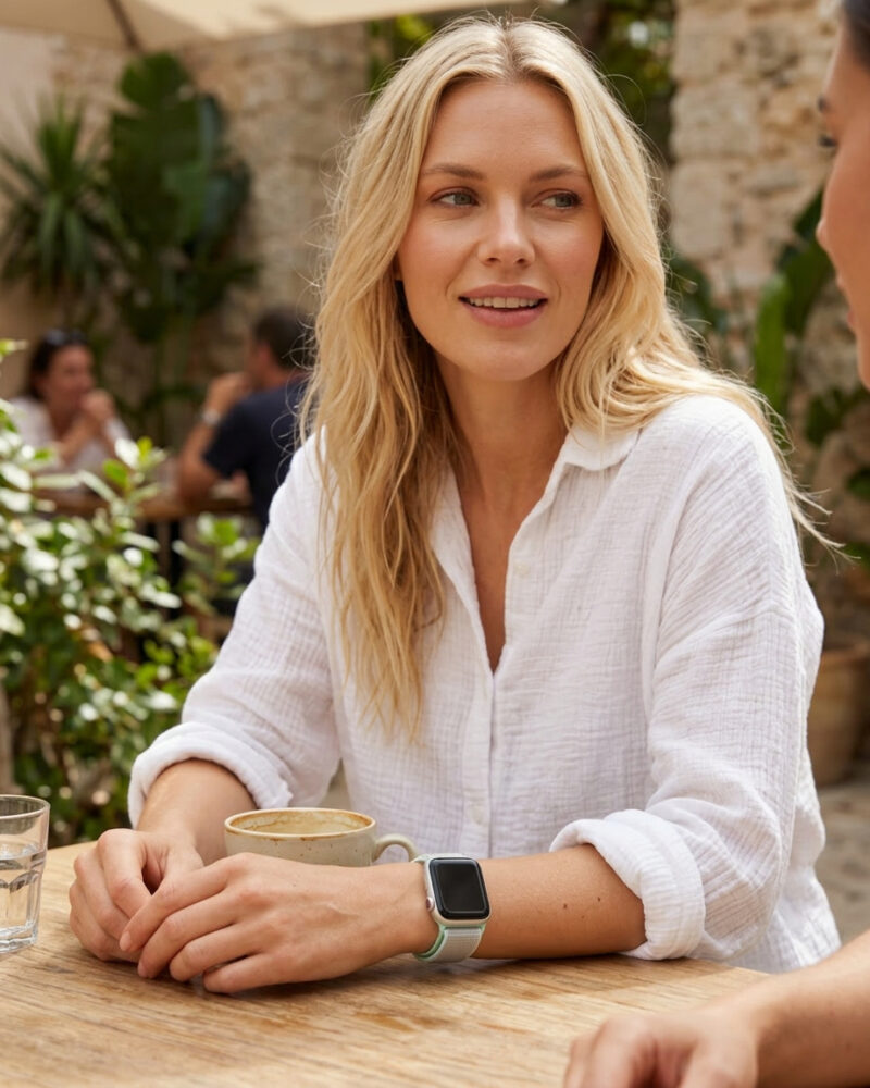 Woman wearing teal tint sport loop smartwatch at outdoor café table