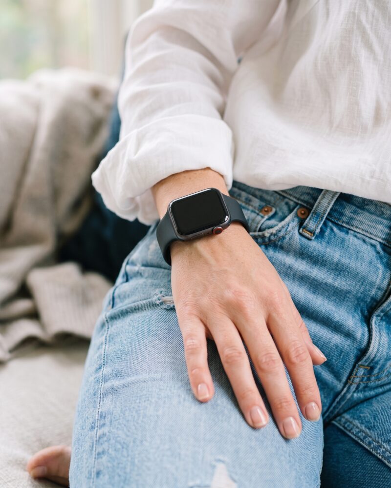 Woman wearing black sport smartwatch band with white shirt and jeans