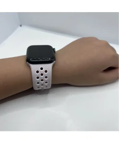 Black smartwatch with white perforated sport band on wrist