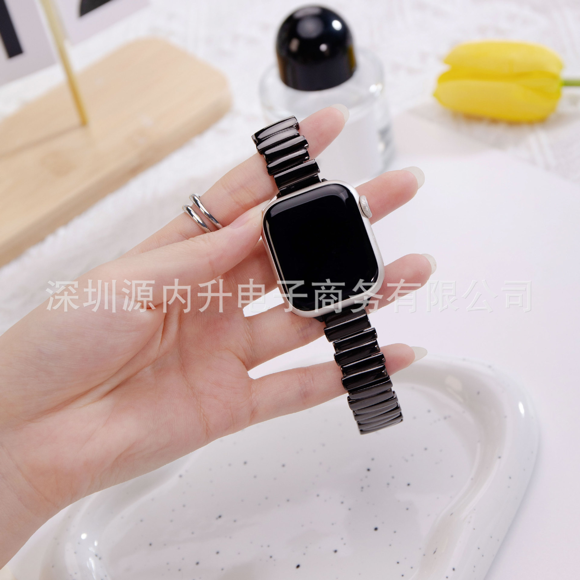 Black ceramic metal smartwatch band with silver case held in hand