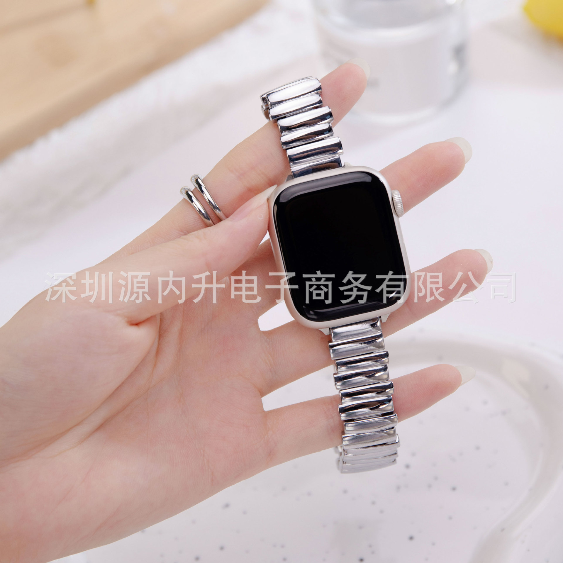 Silver metal link band smartwatch strap held in hand, closeup view