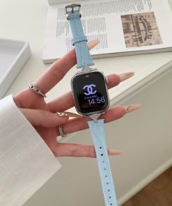 Lake blue leather Apple Watch band with silver charm detail, displayed on wrist