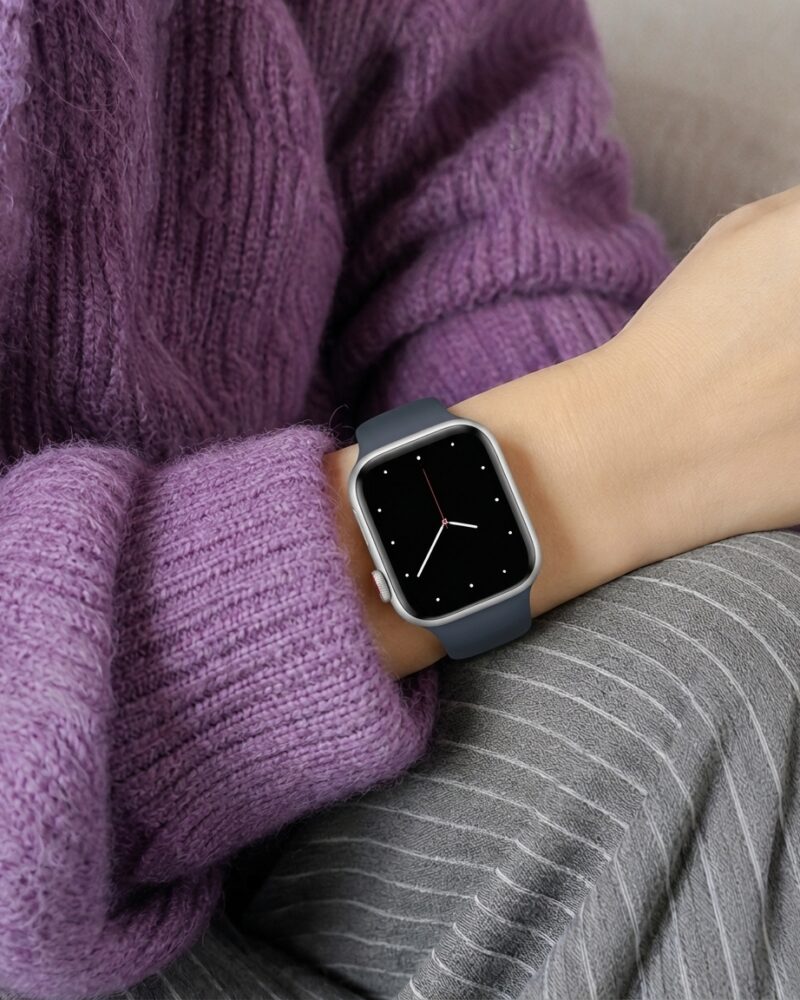 Smartwatch with storm blue sport band worn on wrist with purple sweater